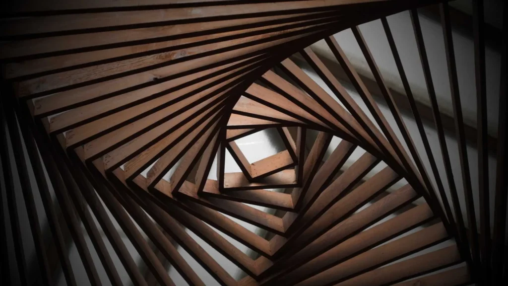 Boutique architectural woodworker installing a custom parametric 3D timber cladding spiral vortex structure inside a luxury commercial facility.